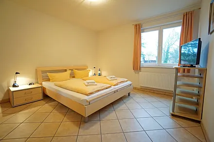 Schlafzimmer mit Doppelbett und Fernseher