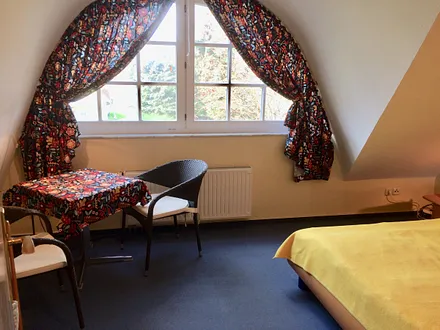 Geräumiges Schlafzimmer mit kleiner Sitzgruppe und Holz-Kinderbett (1,20 mal 0,60 m)