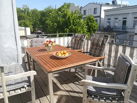 Blick auf die Sonnenterrasse und mit Linden bewachsene Straße
