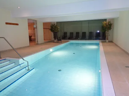 Wellnessbereich mit Schwimmbad und Ruheraum im Hintergrund