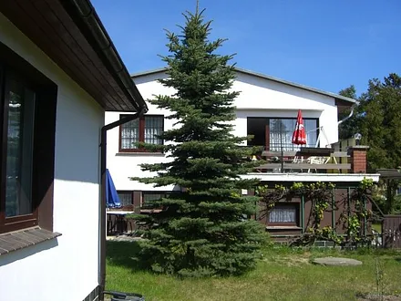 Ferienhaus  (Fenster Wohnzimmer mit Blick in den Garten), im Hintergrund Wohnhaus der Vermieter 