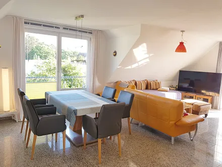 Helles Wohnzimmer mit komfortabler Echtledergarnitur und herrlichem Panoramawasserblick, exklusiver Natursteinboden in der gesamten Wohnung