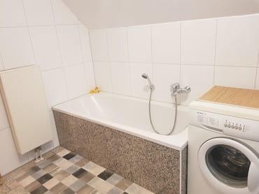 Eine Badewanne lädt zum Relaxen ein, das Luxusbadezimmer verfügt über einen modernen Natursteinboden
