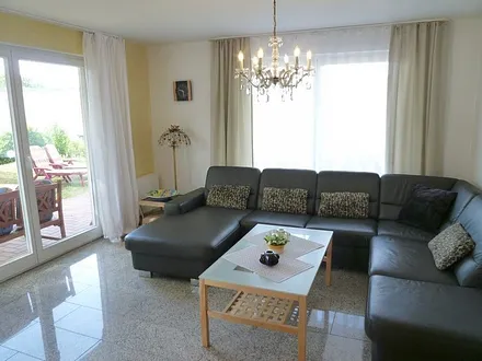 Großzügiges, helles Wohnzimmer mit drei großen Terrassentüren, exklusiver Natursteinboden in der gesamten Wohnung