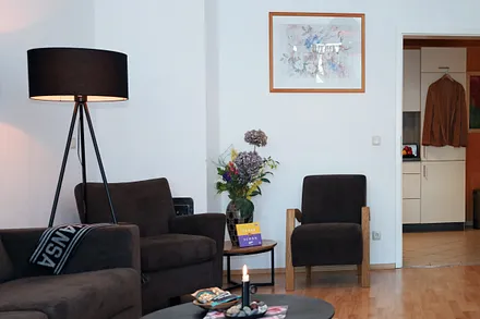 Sie stehen gerade im Flur und blicken durch die Küche in das Wohnzimmer.... Links geht es in das Bad, wo sich auch der Trockner und die Waschmaschine befindet.