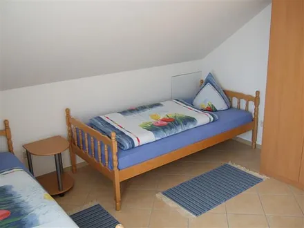 Helles Kinderzimmer mit zwei Einzelbetten, Kleiderschrank und Platz zum Spielen