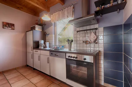 Komplett ausgestattete Küche mit Herd, Backofen, Kühlschrank und Kleingeräten