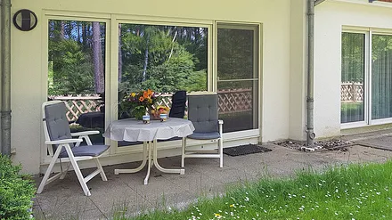 Terrasse mit Mobiliar, links vorm Wohnzimmer überdacht, rechts vorm Schlafzimmer