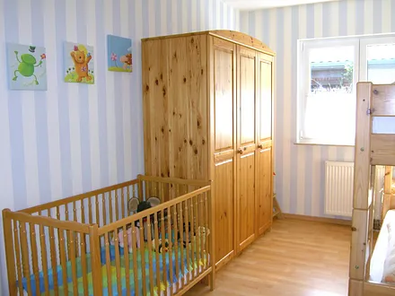 Kinderzimmer mit Etagenbett sowie Kinderbett und Hochstuhl