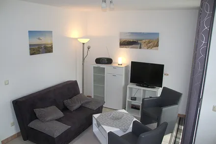 Wohnbereich mit Sofa, Sessel und Flachbild-TV