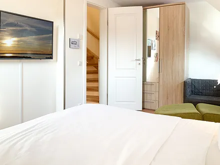 Im 2. Schlafzimmer OG befinden sich eine kleine Couch, ein Kindertisch und ein großer Kleiderschrank.