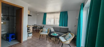 Wohnzimmer mit Schlafcouch und Bad 