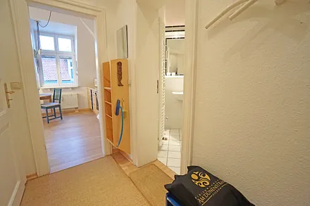 Kleiner Eingangsflur mit Schuhregal und Garderobe führt in den Wohn- Küchenbereich