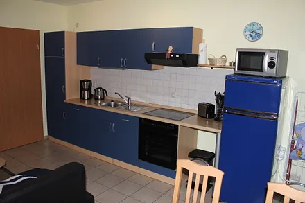 Küchenzeile mit Herd, Kühlschrank, Kaffeemaschine, Wasserkocher, Toaster.