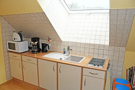 Separate Küche mit Schlafcouch für 1 Person, Ceranfeld (2 Felder), Kühlschrank mit Gefrierfach, Mikrowelle, Kaffeemaschine, Wasserkocher, Toaster und diversen Küchenutensilien.