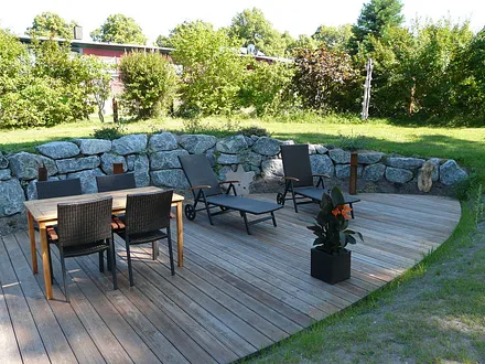 große Terrasse mit Bestuhlung und Liegen im äußeren Gartenbereich