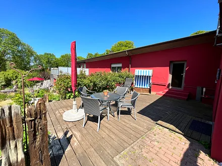 Terrasse mit Strandkorb, Sitzgruppe, Sonnenschirm und Holzkohlegrill