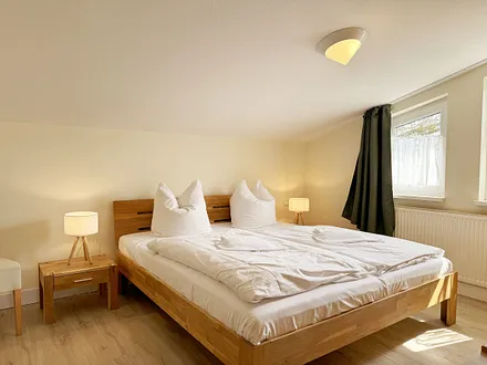 Schlafzimmer mit Doppelbett, Kleiderschrank, Nachttischkonsolen