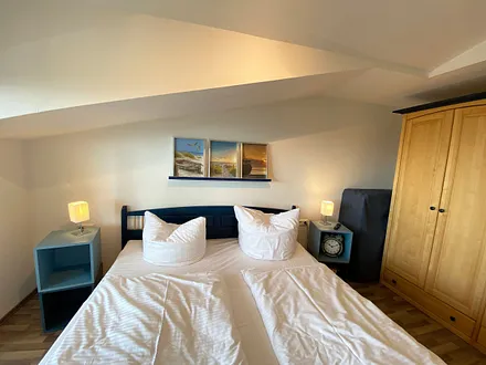 Schlafzimmer mit Doppelbett, Kleiderschrank, Nachttischkonsolen