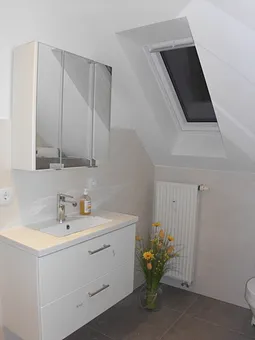 Ein geräumiges Badezimmer mit modernem Waschtisch runden das Bild dieser gemütlichen Wohnung ab. 