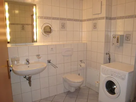 Blick ins großzügige Bad mit Münzwaschmaschine, Fön und Kosmetikspiegel.