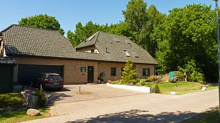 Haus am Wald - Frontansicht mit Parkbereich und Fahrrad-Abstellraum am linken Bildrand