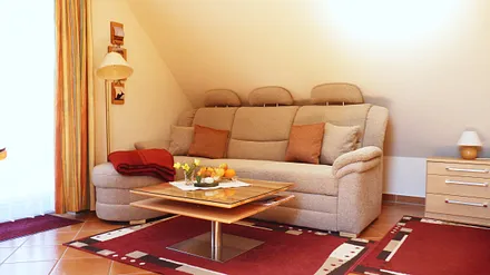 Couchecke mit Tisch und Standleuchte (ggf. ausklappbar zur Doppelbettliege bei Aufbettung) im Wohnbereich für den gemütlichen Teil des Abends oder bei "Schietwetter"