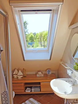 Duschbad, gefliest inkl. Fußboden und Wandheizung, ausgestattet mit Waschtisch, Ablage und Spiegel, WC und Dusche, komplettiert mit ensprechendem Badaccessoires