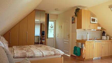 Haupt- und Badeingang (rechts) mit Blick vom Wohn-/Schlafbereich, ausgestattet mit Doppelbett inkl. beids. Nacht- und Einbauschranken, vollst. gefliest mit Fußboden- und Wandheizung