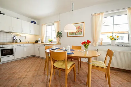 Esstisch un im Hintergrund die komplett eingerichtete Küchenzeile