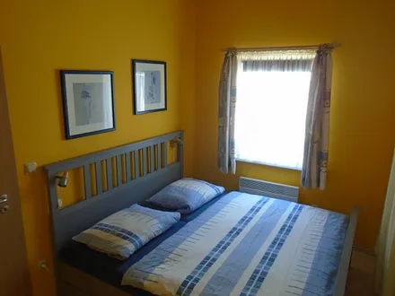 Schlafzimmer mit Doppelbett 180x200 cm, am Fenster befindet sich ein Verduncklungsrollo