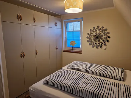 Schlafzimmer 1 im 1. OG mit Doppelbett, angrenzendem Duschbad und TV