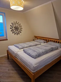 Schlafzimmer 1 im 1. OG mit Doppelbett, angrenzendem Duschbad und TV