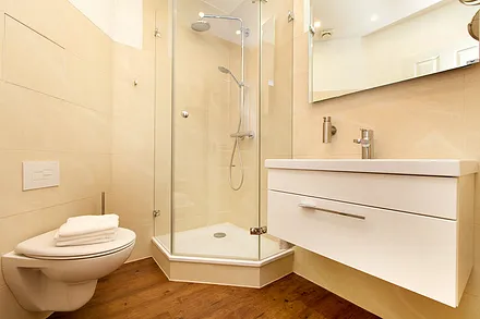 Das schicke Bad mit großem Waschtisch, Echtglasdusche und Regenbrause sowie WC und Fön.