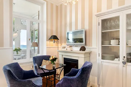 Am Kamin (elektr.) ist die Fernsehecke mit großem Flachbild-TV eingerichtet. Auch von hier sehen Sie das Meer.