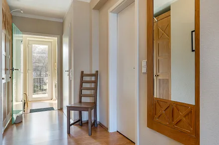 Blick durch den Flur mit Kleiderschrank zum Eingangsbereich. Rückwärtig tritt man aus der Wohnung auf einen überdachten Laubengang/Gemeinschaftsbalkon.