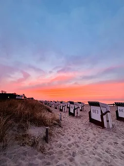 Küstenzauber: Strandkörbe im Sonnenuntergang & goldenes Licht. 