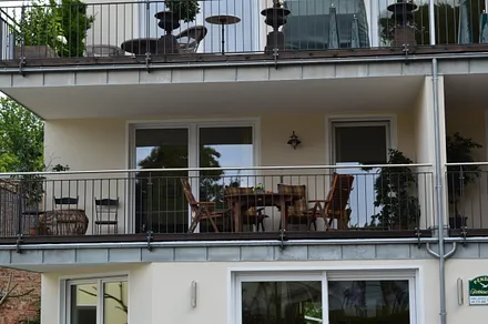 Detailansicht des großen Balkones mit Tisch und Stühlen zum Erholen.
