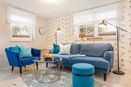 Die Fenster im Wohnzimmer sind mit Raffgardinen und Verdunkelungsplisses bestückt.