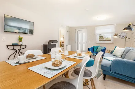 Blick durch das Wohnzimmer mit Flat-TV und Kaminofen. WLAN ist kostenfrei.