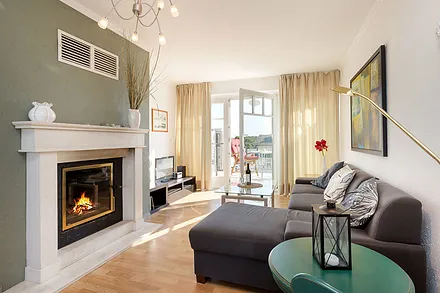 Hier sehen Sie das Wohnzimmer mit Blick zum Balkon. Der Kamin ist mit Holz beheizbar.