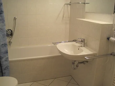 Badezimmer mit Wanne und Waschmaschine, Föhn, Putzmittel