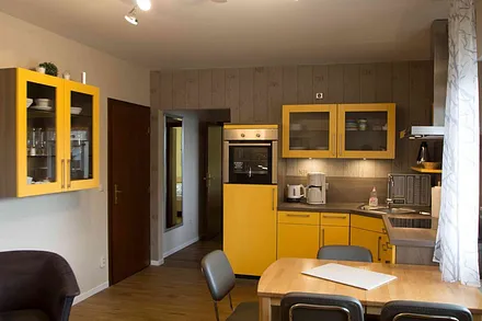 Ansicht Küchenzeile mit Spülmaschine, Backofen und Essbereich im Wohnzimmer