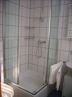 Im Badezimmer befindet sich ein WC, eine Dusche und ein Waschbecken. Das Bad hat ein eigenes Fenster.