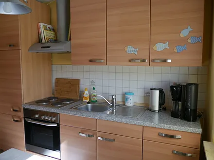 Küchenzeile mit Herd, Backofen, Wasserkocher, Kaffeemaschine sowie genügend Geschirr.