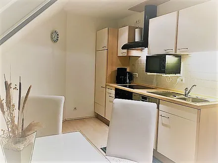 Blick in die moderne Küche im cremeweißen Ton mit Essecke