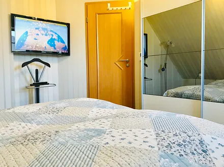 Schlafzimmer mit Doppelbett, Fernseher und Schrank