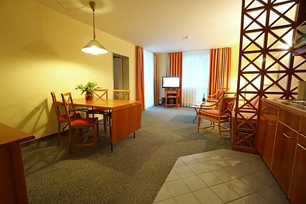 Wohnzimmer mit Schlafcouch, Esstisch und Küchenzeile