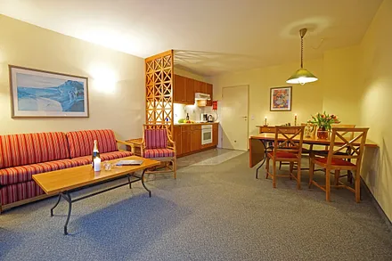 Wohnzimmer mit Schlafcouch, Esstisch und Küchenzeile