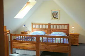 Oberes Schlafzimmer mit einem Doppel- und einem Einzelbett. Die Fenster sind mit Rollos zur Abdunkelung ausgestattet.